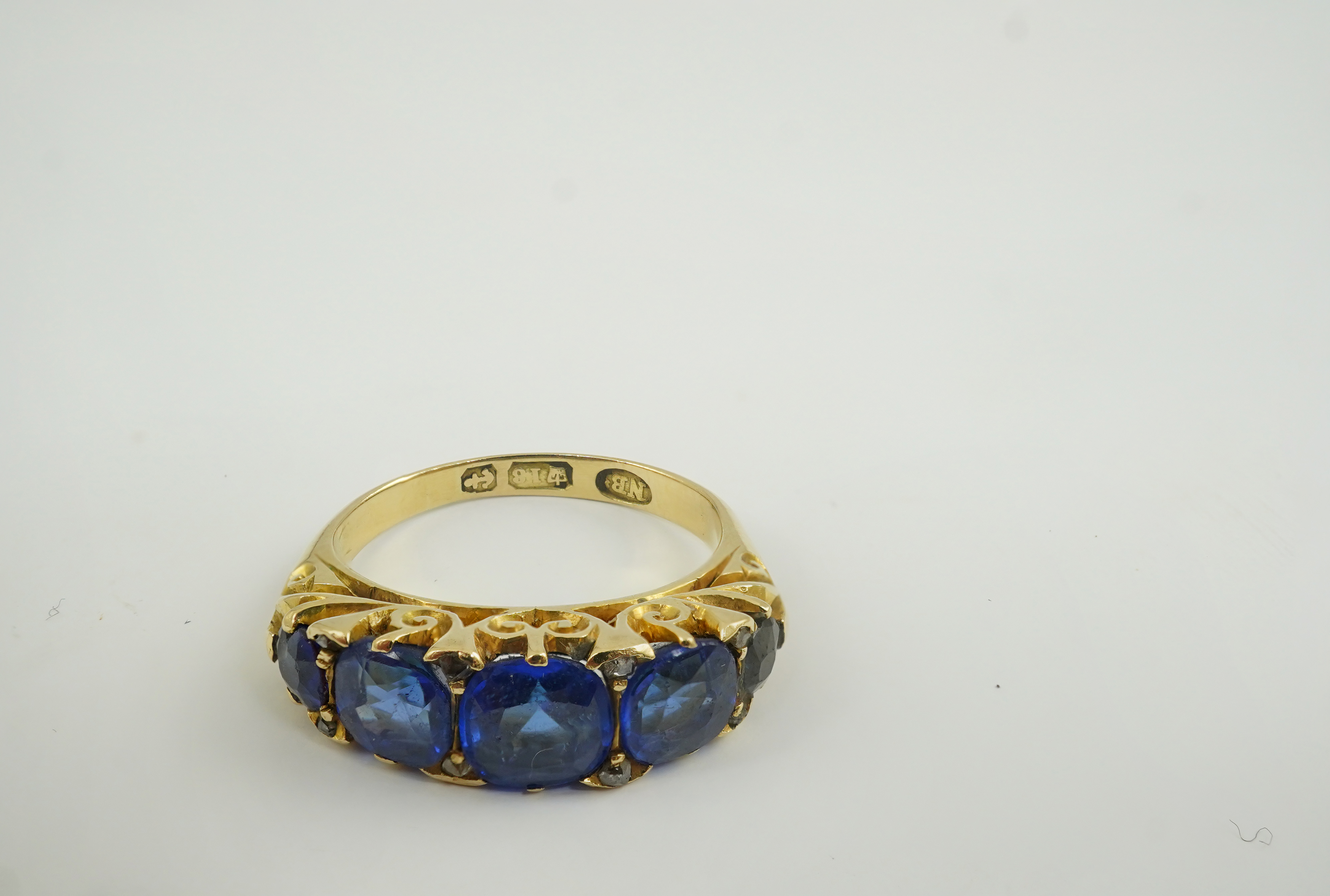 A late Victorian 18ct gold and graduated five stone blue doublet set half hoop ring